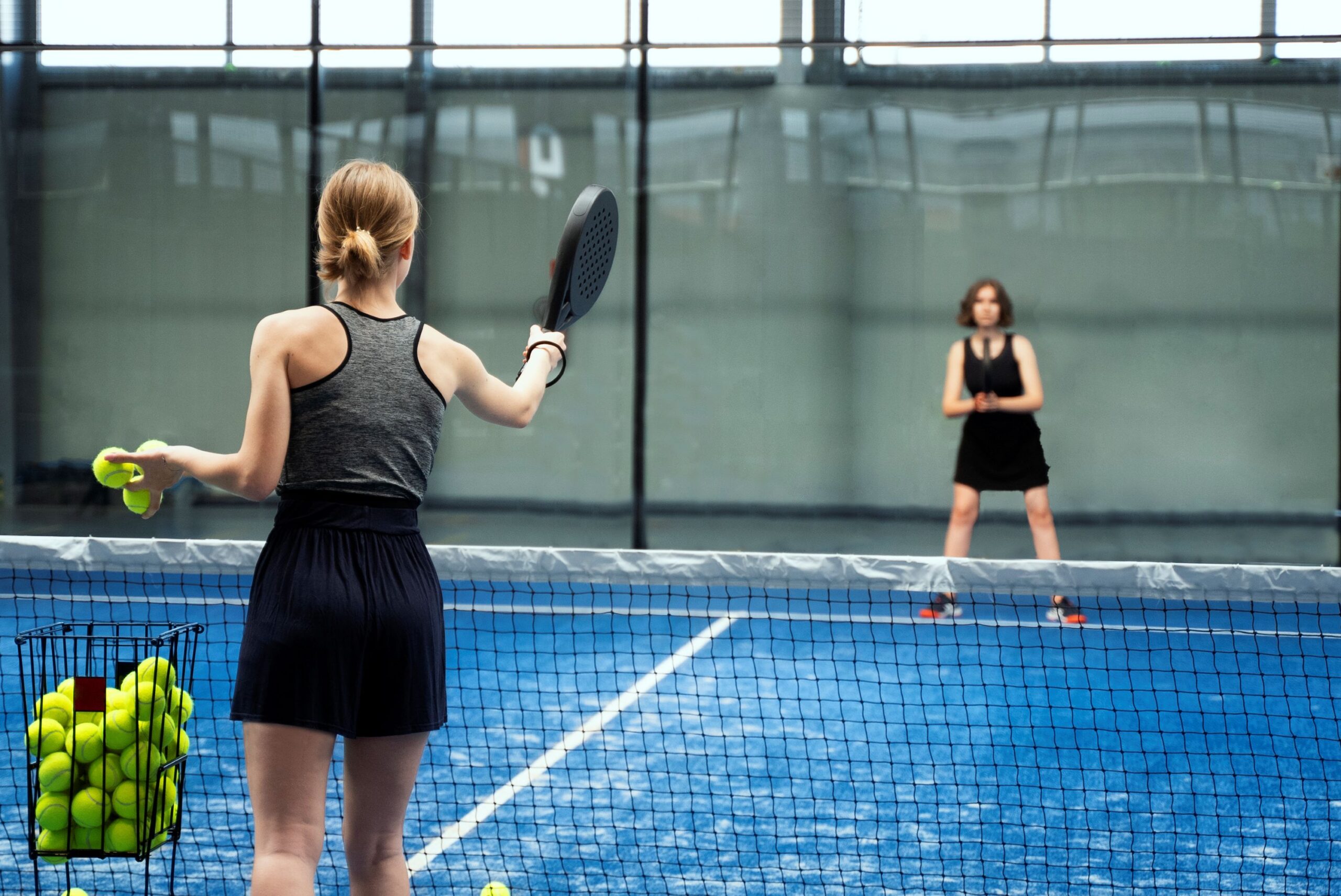 Padelį žaidžiantys žmonės sporto aikštelėje